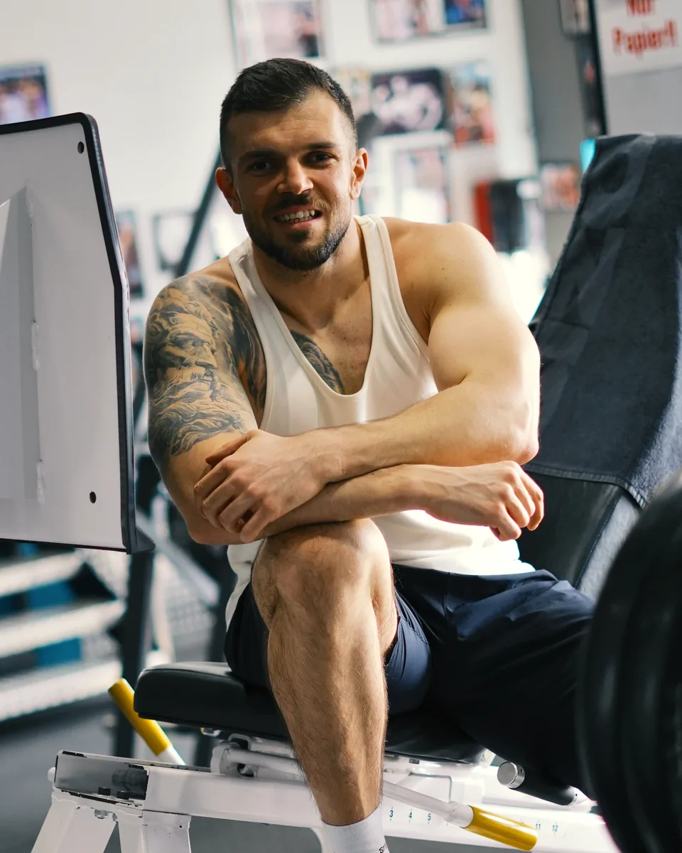 Adnan Lojic lächelnd an der Beinpresse im Fitnessstudio
